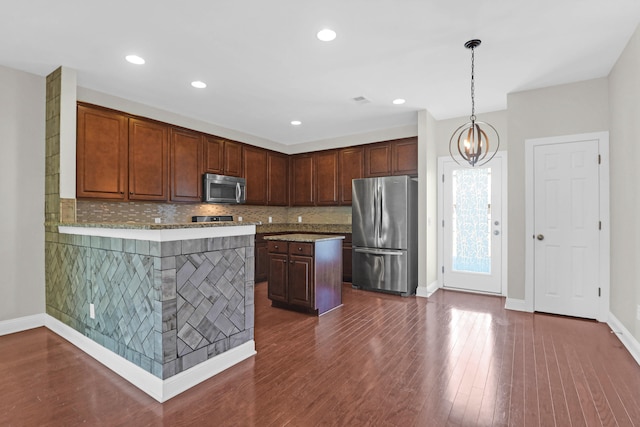 kitchen featuring dark hardwood / wood-style flooring, backsplash, stainless steel appliances, an inviting chandelier, and hanging light fixtures