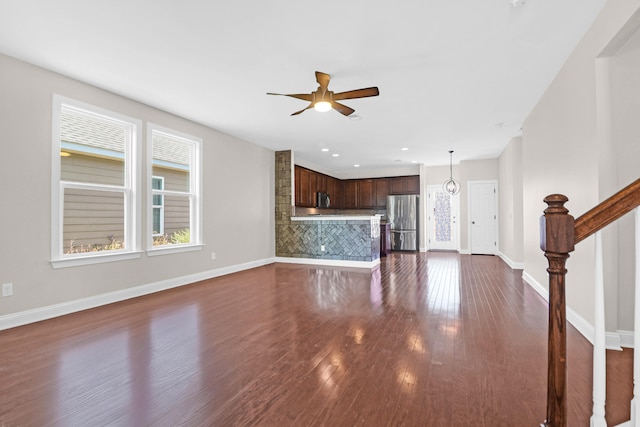 unfurnished living room featuring ceiling fan and dark hardwood / wood-style flooring