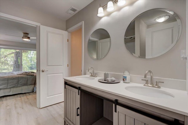 bathroom with double sink vanity, wood-type flooring, and ceiling fan