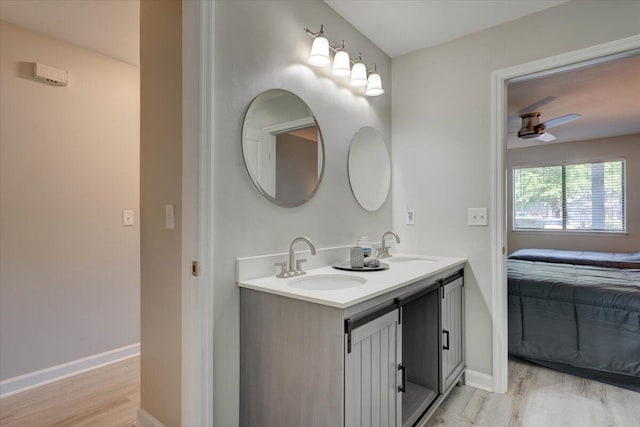 bathroom featuring vanity with extensive cabinet space, double sink, wood-type flooring, and ceiling fan