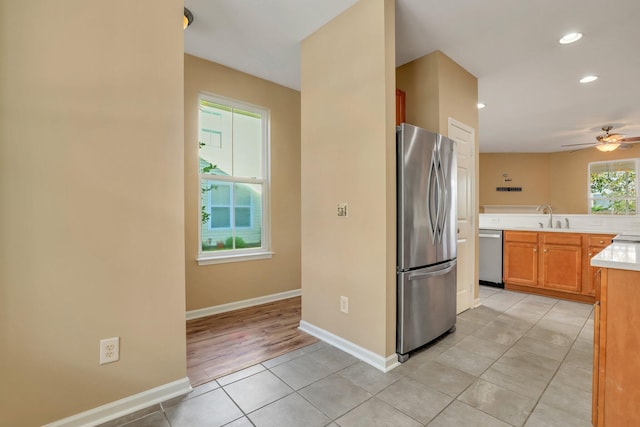 kitchen with light wood-type flooring, stainless steel appliances, ceiling fan, and sink