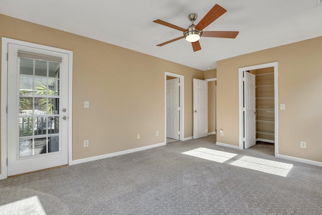 unfurnished bedroom featuring light colored carpet, a spacious closet, and ceiling fan