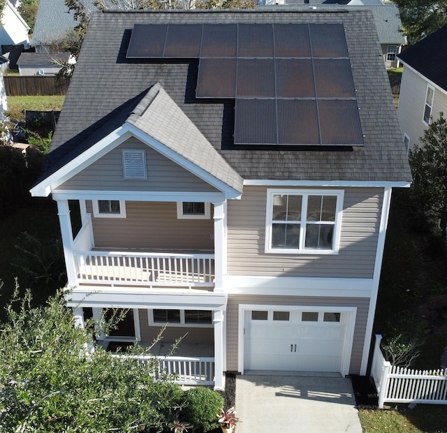 view of front of house featuring solar panels, a balcony, and a garage