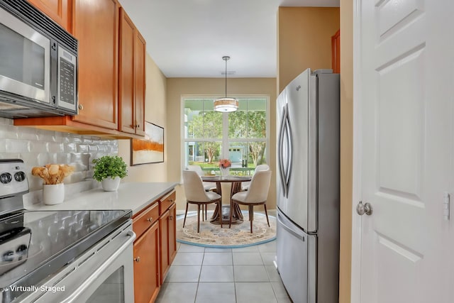 kitchen with appliances with stainless steel finishes, backsplash, decorative light fixtures, and light tile patterned flooring