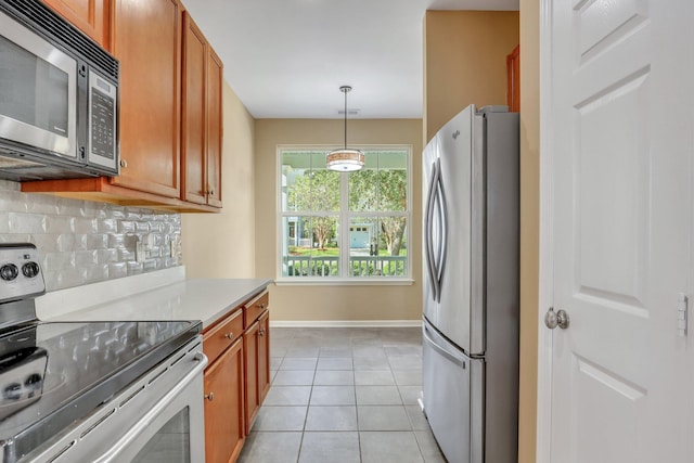 kitchen with decorative backsplash, light tile patterned floors, pendant lighting, and appliances with stainless steel finishes