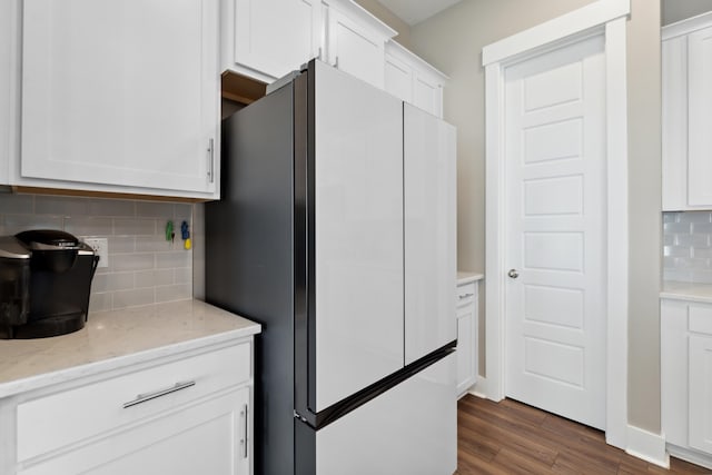 kitchen with white cabinets, stainless steel fridge, light stone countertops, tasteful backsplash, and dark hardwood / wood-style flooring