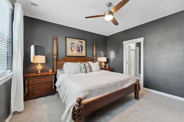 bedroom with light colored carpet, ensuite bath, and ceiling fan