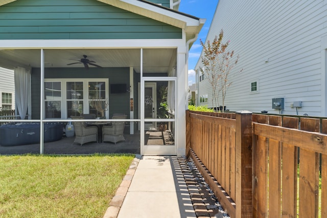 view of exterior entry featuring a lawn, a patio area, and ceiling fan