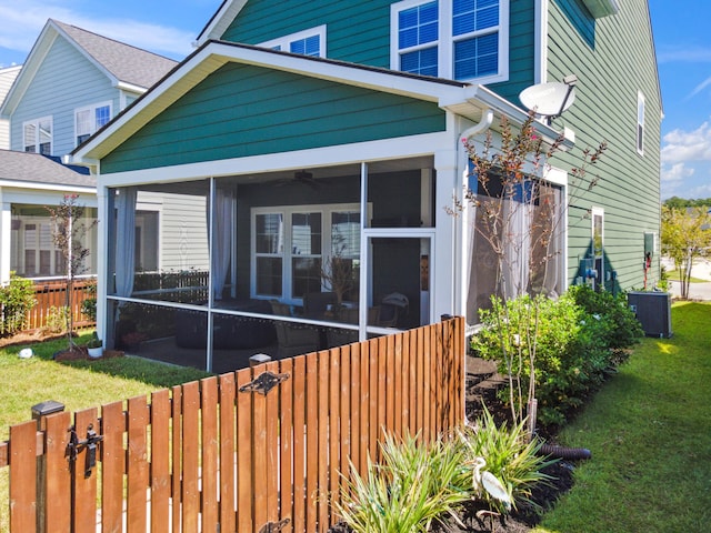 exterior space featuring a yard, central air condition unit, and a sunroom