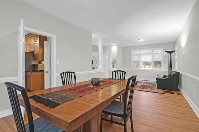 dining space with decorative columns and light hardwood / wood-style flooring