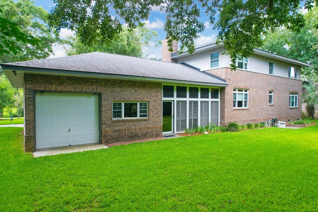 rear view of property featuring a garage and a lawn