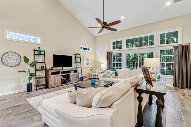 living room featuring ceiling fan, light wood-type flooring, plenty of natural light, and high vaulted ceiling