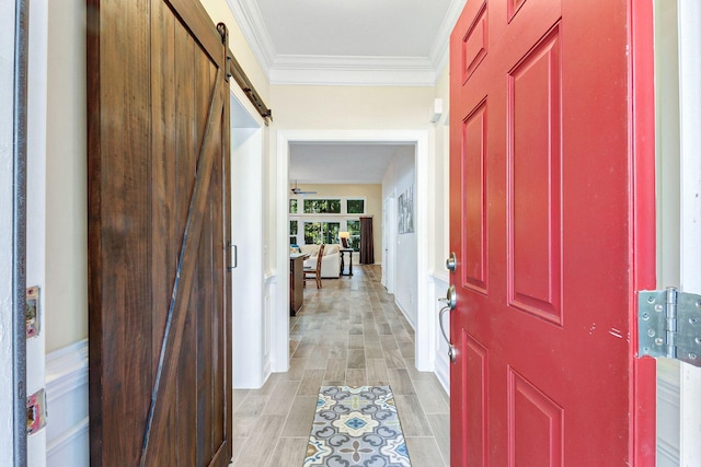 foyer with light wood-type flooring, crown molding, and a barn door