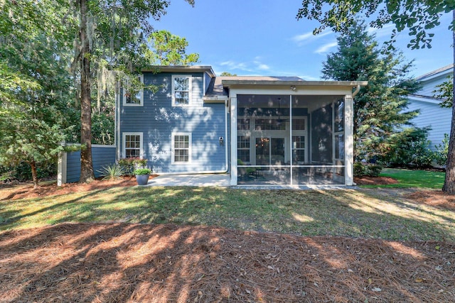 rear view of house with a sunroom, a patio area, and a lawn