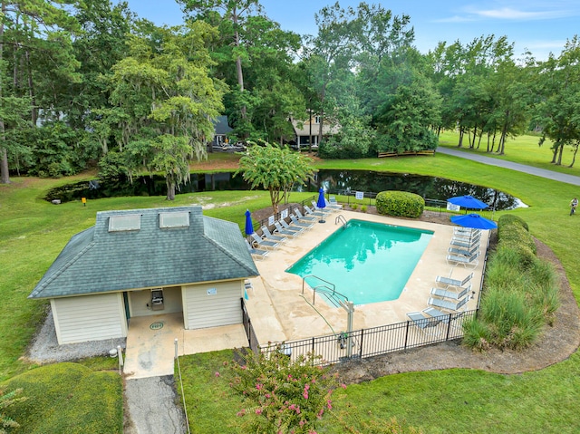 view of swimming pool featuring a water view, a yard, and a patio