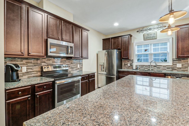 kitchen with pendant lighting, sink, tasteful backsplash, stainless steel appliances, and light stone countertops