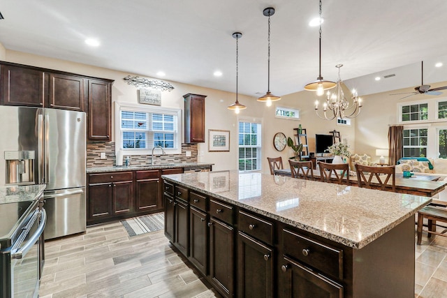 kitchen featuring decorative light fixtures, ceiling fan with notable chandelier, plenty of natural light, and a kitchen island