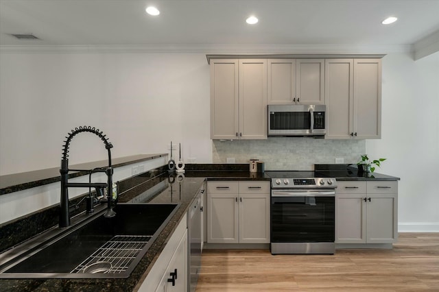 kitchen with visible vents, crown molding, appliances with stainless steel finishes, tasteful backsplash, and a sink