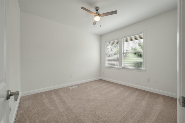 spare room with baseboards, ceiling fan, visible vents, and light carpet