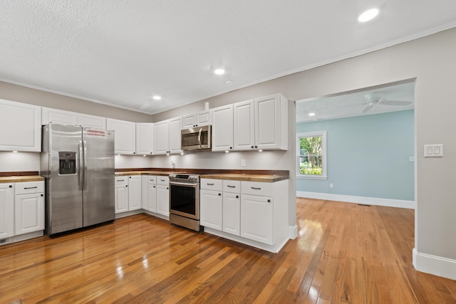 kitchen with appliances with stainless steel finishes, light hardwood / wood-style flooring, white cabinets, and ceiling fan