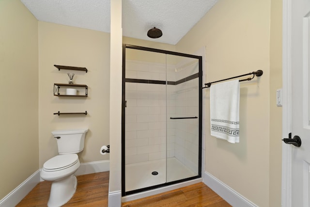 bathroom with an enclosed shower, wood-type flooring, a textured ceiling, and toilet