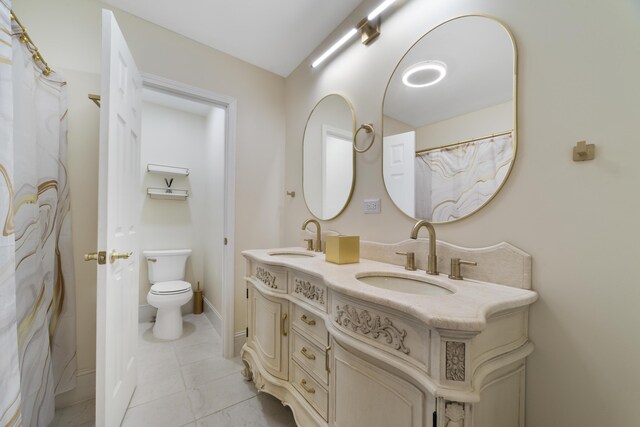 bathroom featuring dual vanity, tile patterned flooring, and toilet