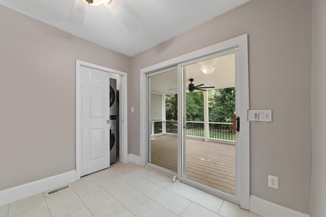 doorway featuring ceiling fan, stacked washer / drying machine, and light tile patterned floors