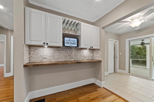 kitchen featuring ceiling fan, light wood-type flooring, white cabinetry, and decorative backsplash