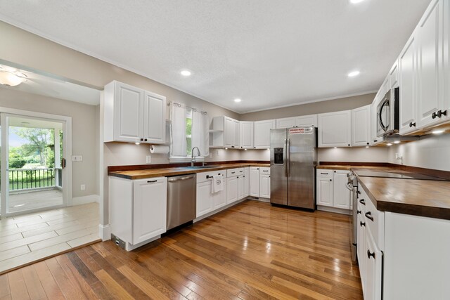 kitchen with wooden counters, stainless steel appliances, plenty of natural light, and light hardwood / wood-style floors