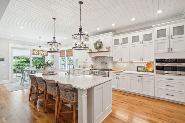 kitchen with white cabinets, sink, a kitchen island with sink, and appliances with stainless steel finishes