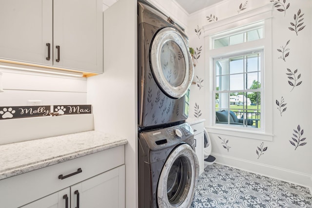 laundry area with light tile patterned floors, cabinets, and stacked washer / drying machine