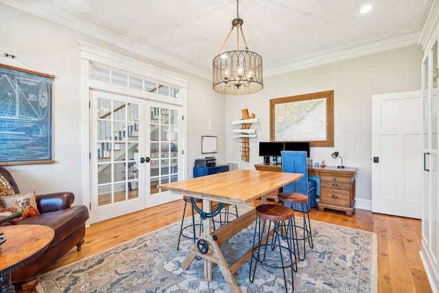 dining space with crown molding, french doors, an inviting chandelier, and light hardwood / wood-style flooring