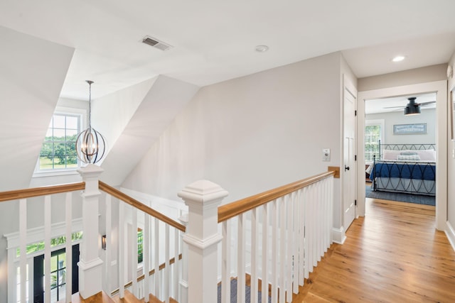 hall with light wood-type flooring and an inviting chandelier