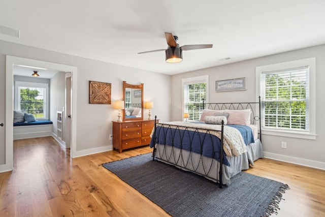 bedroom featuring ceiling fan, light hardwood / wood-style floors, and multiple windows