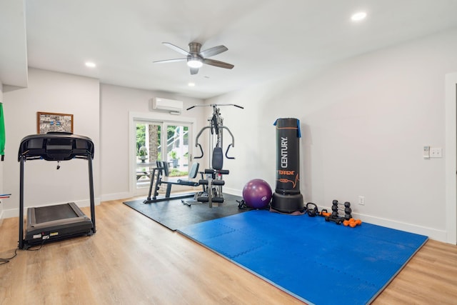 workout room featuring hardwood / wood-style floors, ceiling fan, and a wall mounted AC