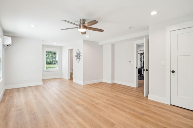 unfurnished room featuring ceiling fan, a wall mounted air conditioner, and light wood-type flooring