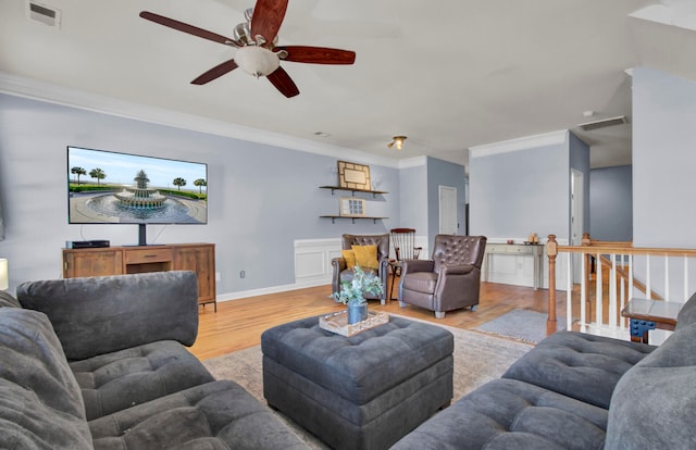 living room with light hardwood / wood-style floors, ceiling fan, and ornamental molding