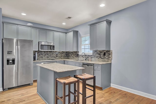 kitchen featuring a breakfast bar, sink, light hardwood / wood-style flooring, appliances with stainless steel finishes, and a kitchen island