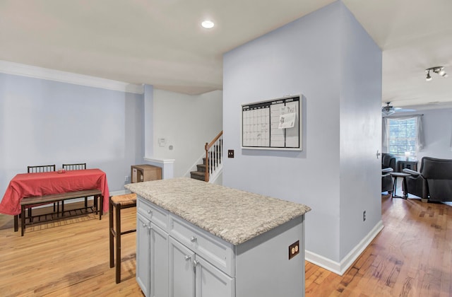kitchen with ceiling fan, a kitchen island, ornamental molding, and light hardwood / wood-style flooring