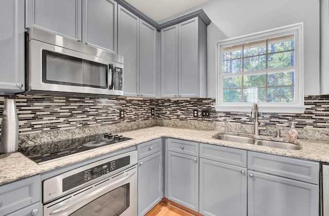 kitchen with decorative backsplash, light stone countertops, sink, and appliances with stainless steel finishes