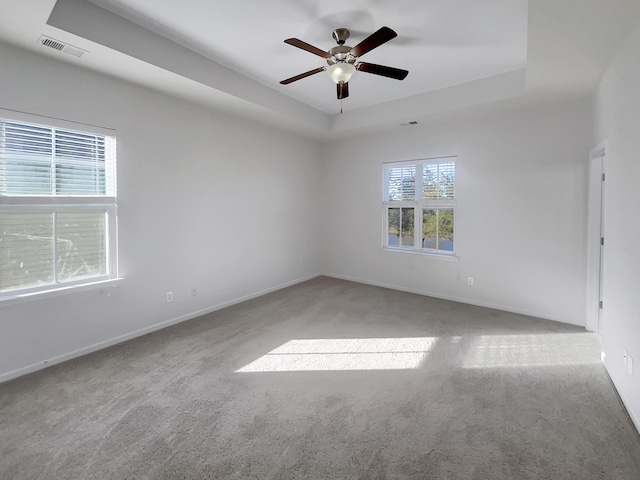 carpeted spare room featuring a raised ceiling and ceiling fan