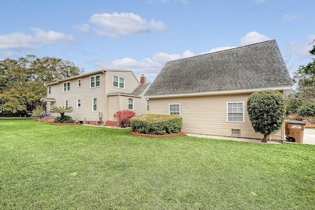 rear view of house with crawl space, roof with shingles, a chimney, and a yard