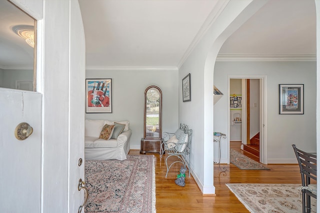 interior space featuring arched walkways, light wood-style flooring, baseboards, stairs, and ornamental molding