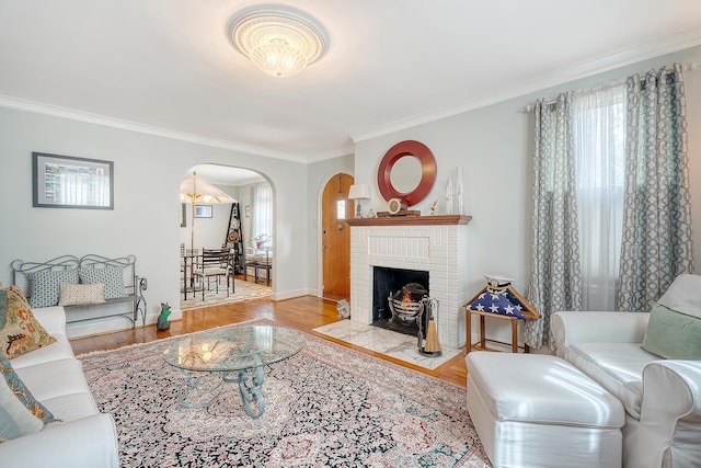 living room featuring arched walkways, ornamental molding, wood finished floors, and a wealth of natural light