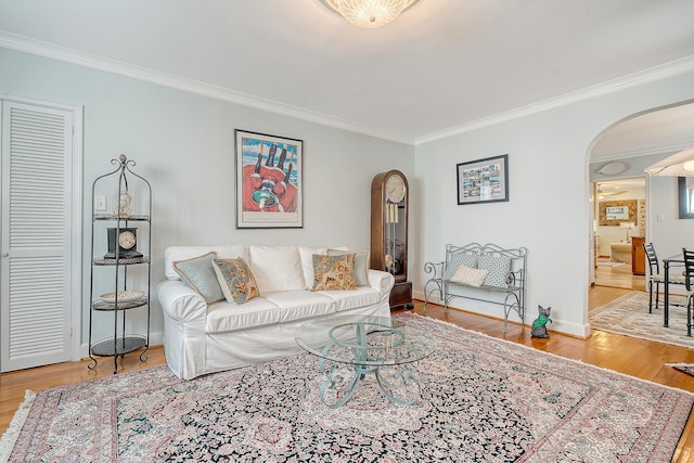 living room with baseboards, arched walkways, crown molding, and wood finished floors