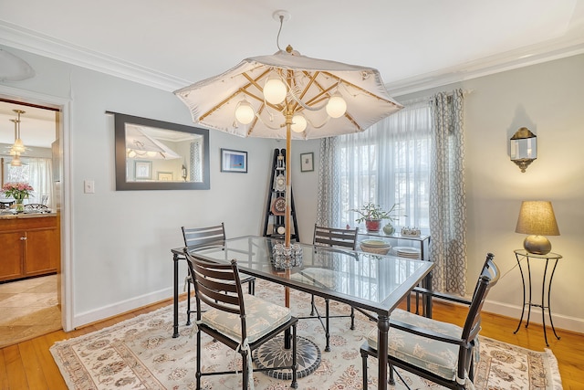 dining space featuring light wood-type flooring, plenty of natural light, ornamental molding, and baseboards