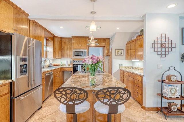 kitchen featuring stainless steel appliances, brown cabinets, a sink, and pendant lighting