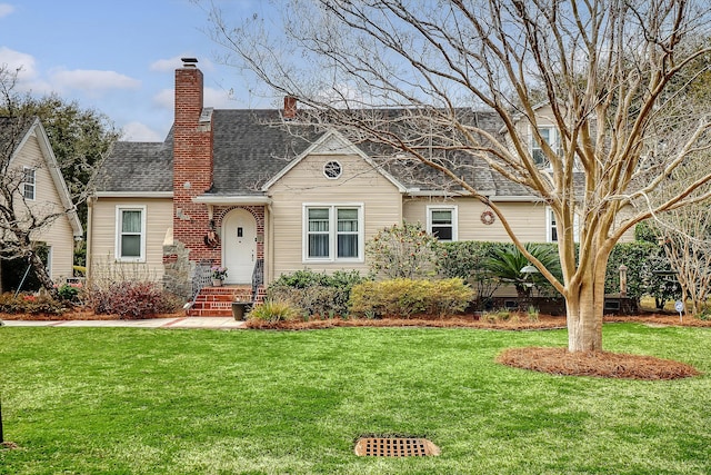 view of front of house featuring a shingled roof, a front yard, and a chimney