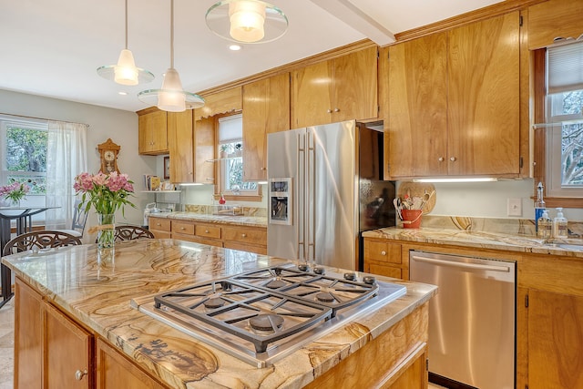 kitchen featuring a kitchen island, light countertops, appliances with stainless steel finishes, brown cabinetry, and decorative light fixtures