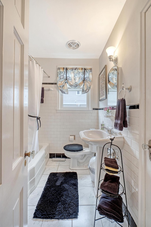 bathroom featuring toilet, visible vents, shower / bath combo with shower curtain, and tile walls